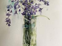 Bluebells with forget me nots in a tall glass vase.