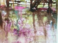 Distant trees with lavender flowers reflected in the river below.