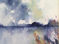 Evening sky above distant blue hills and brown /orange reeds in foreground.