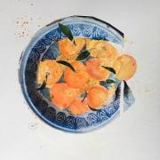 Bright satsumas in a collaged dish.